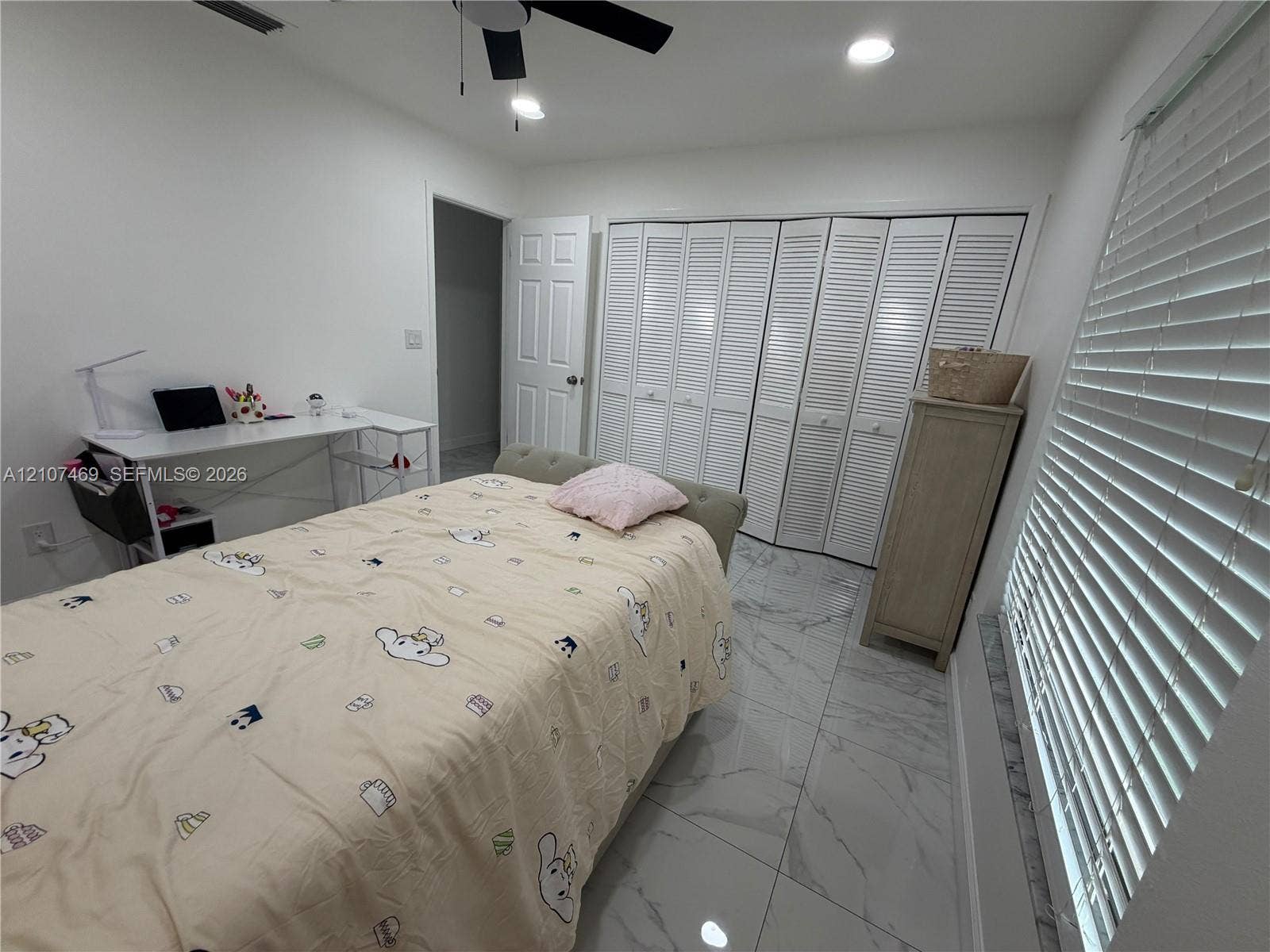 Large-format tile flooring, ceiling fan with integrated lighting, recessed lighting, and wall-to-wall louvered-door closet