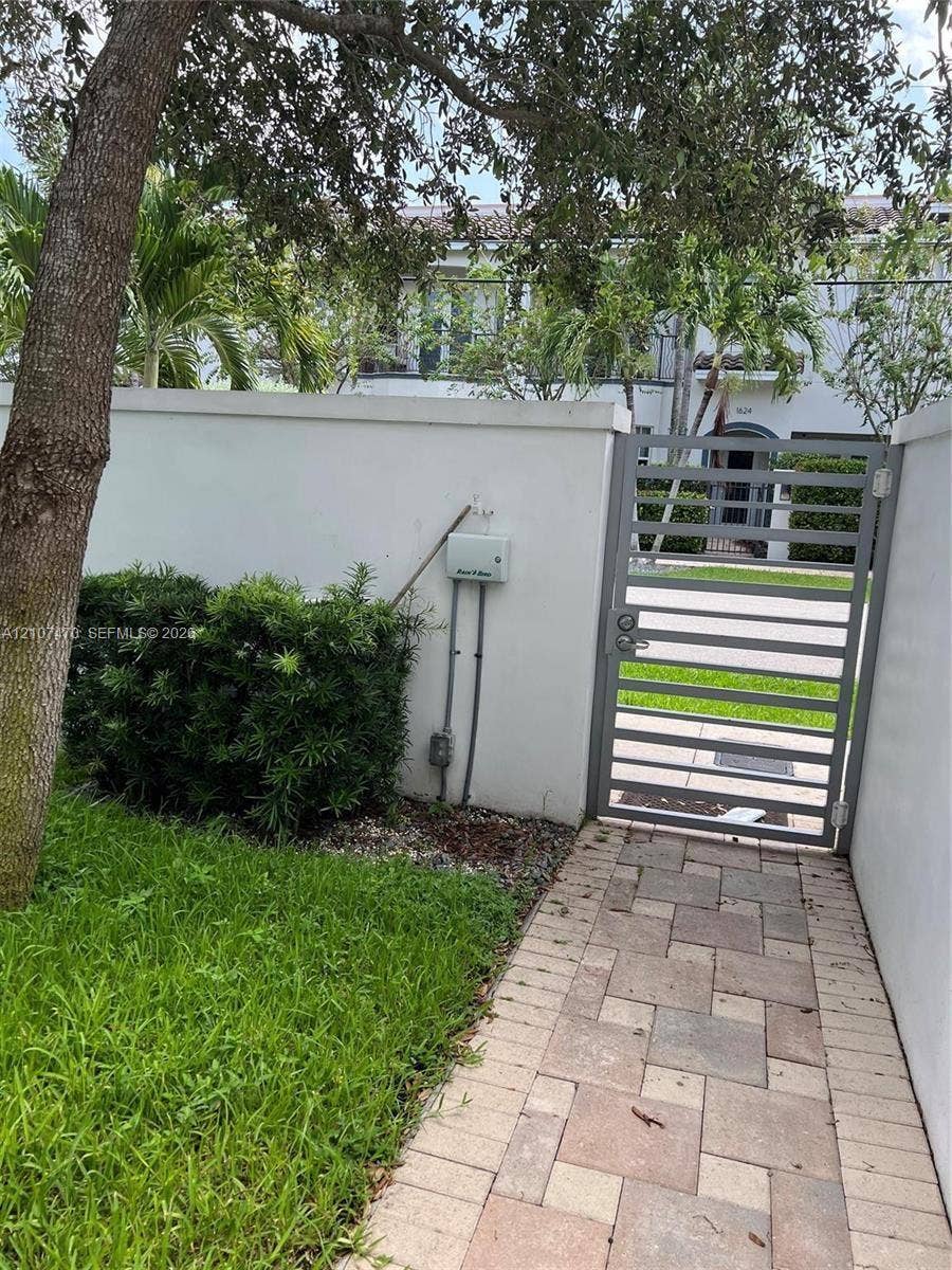 1629 NE 9th Street, #1629, Fort Lauderdale, Fort Lauderdale, FL 33304 Private courtyard entry featuring a paved stone walkway, privacy wall, metal gate, and mature landscaping
