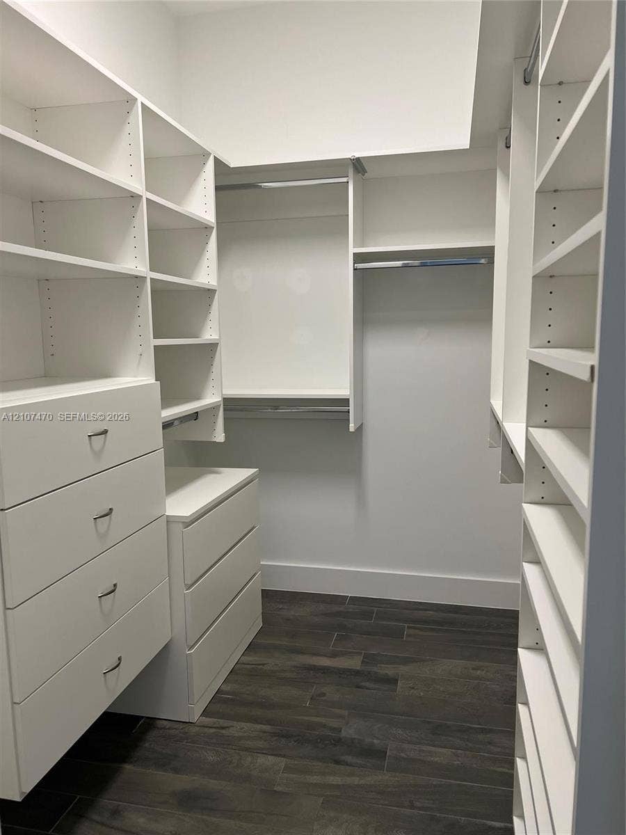 1629 NE 9th Street, #1629, Fort Lauderdale, Fort Lauderdale, FL 33304 Customized walk-in closet featuring floor-to-ceiling white cabinetry, integrated drawer storage, multiple tiered shelving units, and wood-finish flooring