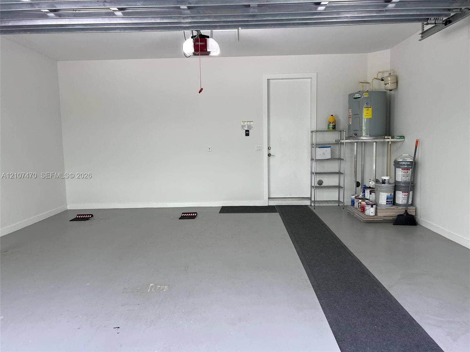 1629 NE 9th Street, #1629, Fort Lauderdale, Fort Lauderdale, FL 33304 Finished garage featuring grey epoxy flooring, neutral wall paint, overhead door opener, and a dedicated utility area with a water heater