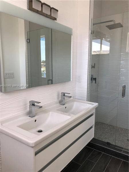 1629 NE 9th Street, #1629, Fort Lauderdale, Fort Lauderdale, FL 33304 Double vanity with rectangular undermount sinks, polished chrome faucets, textured wall tile backsplash, frameless glass shower enclosure, and wood-finish flooring