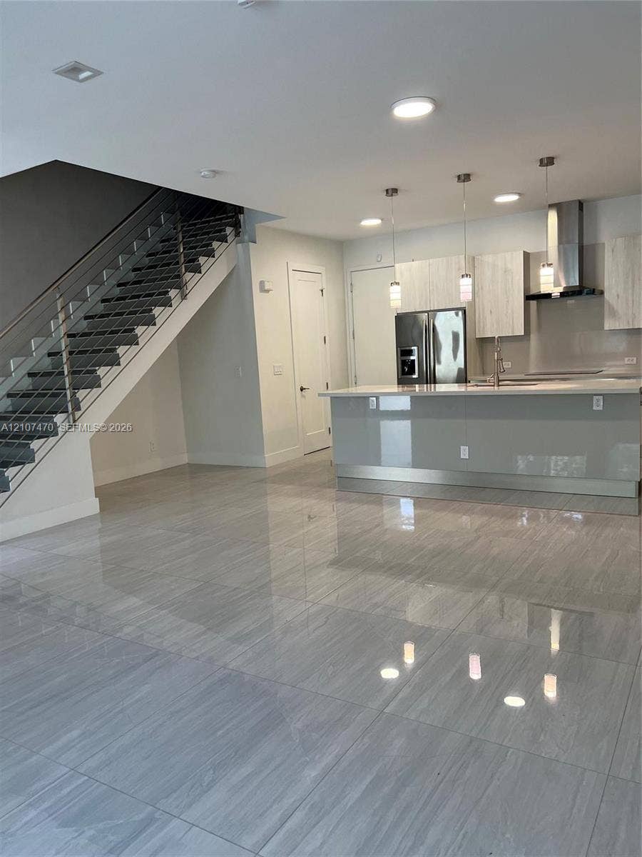 1629 NE 9th Street, #1629, Fort Lauderdale, Fort Lauderdale, FL 33304 Large-format tile flooring throughout the open-concept space, modern kitchen featuring high-gloss cabinetry, a central island with a quartz countertop, and a staircase with stainless steel railings