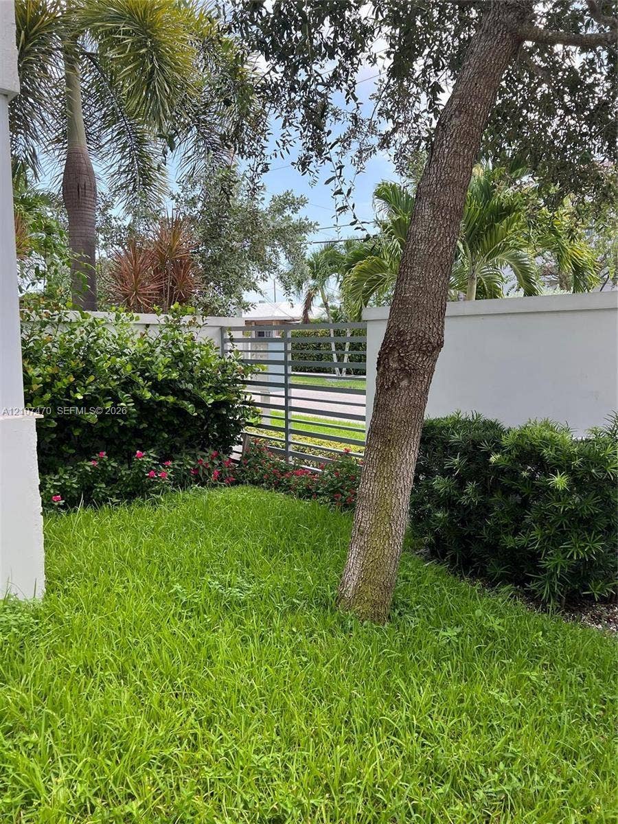 1629 NE 9th Street, #1629, Fort Lauderdale, Fort Lauderdale, FL 33304 Private outdoor space featuring a manicured lawn, perimeter walls, mature palm trees, and horizontal metal fencing