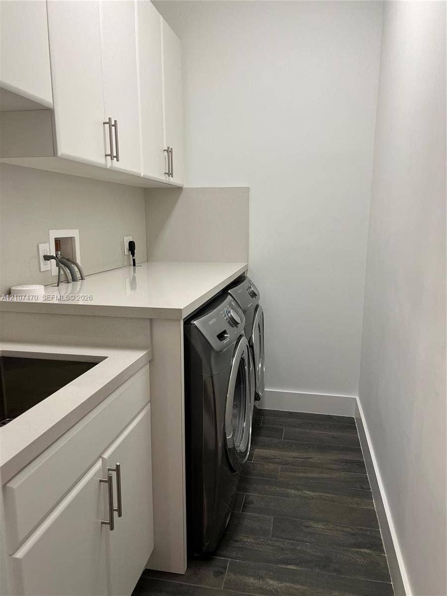 1629 NE 9th Street, #1629, Fort Lauderdale, Fort Lauderdale, FL 33304 Laundry room featuring white cabinetry with brushed-metal pulls, composite countertop, integrated utility sink, and wood-finish tile flooring