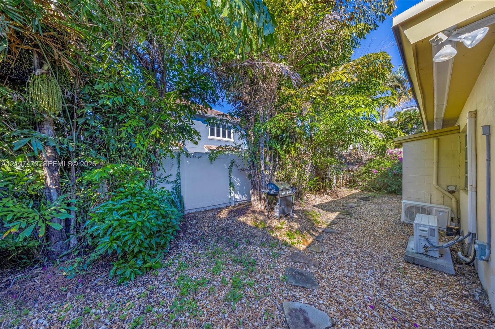 Side yard area featuring gravel ground cover, natural stone paver pathway, and mature tree landscaping