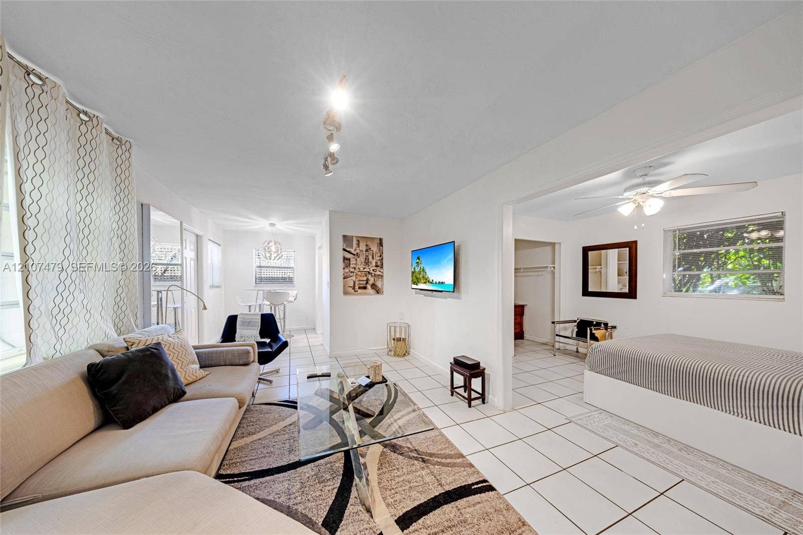 Ceramic tile flooring, multi-directional ceiling track lighting, ceiling fan with integrated light fixture, and large rectangular windows