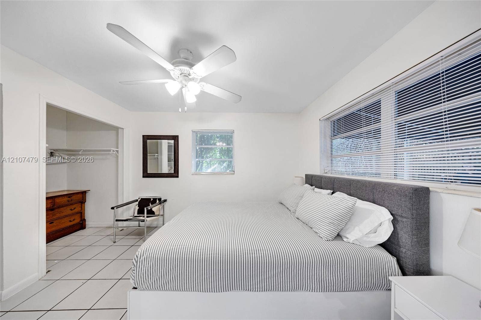 Interior space featuring white ceramic tile flooring, a multi-blade ceiling fan with integrated lighting, and horizontal window blinds