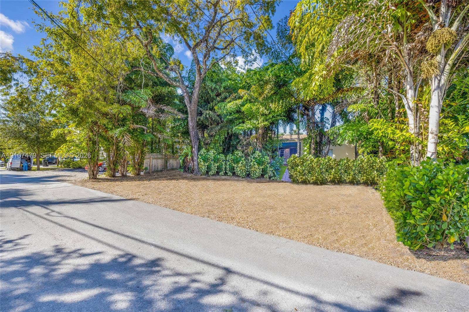 Level lot featuring mature trees, established shrubbery, and a paved street frontage