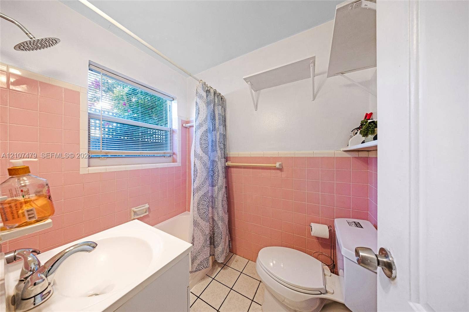 Bathroom featuring pink wall tile, a white vanity with an integrated sink, a porcelain toilet, and square floor tiles