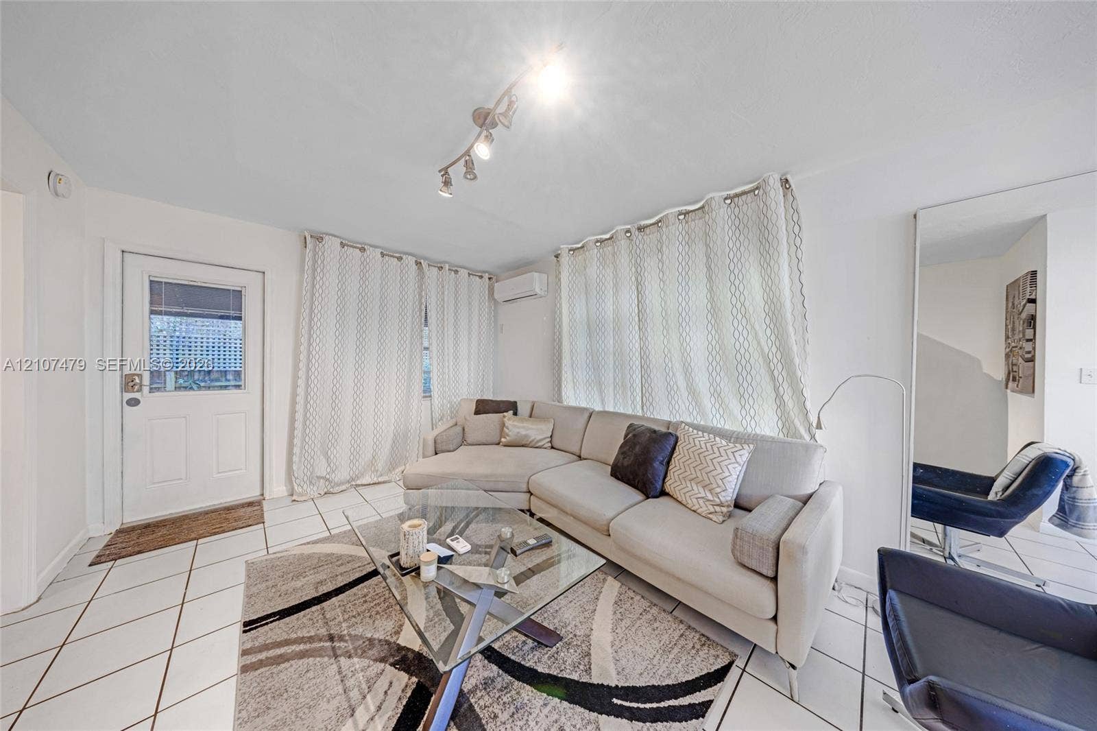 Interior space featuring white tiled flooring, a mounted ductless mini-split HVAC unit, and track lighting