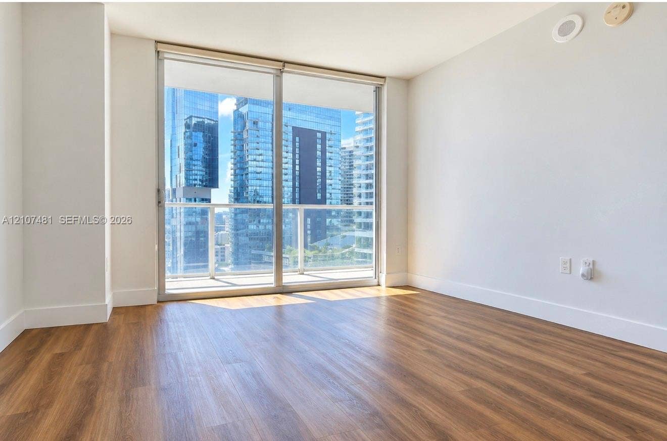 55 SE 6th Street, #2802, Miami, FL 33131 Floor-to-ceiling sliding glass door, private balcony with metal railing, and wood-finish flooring