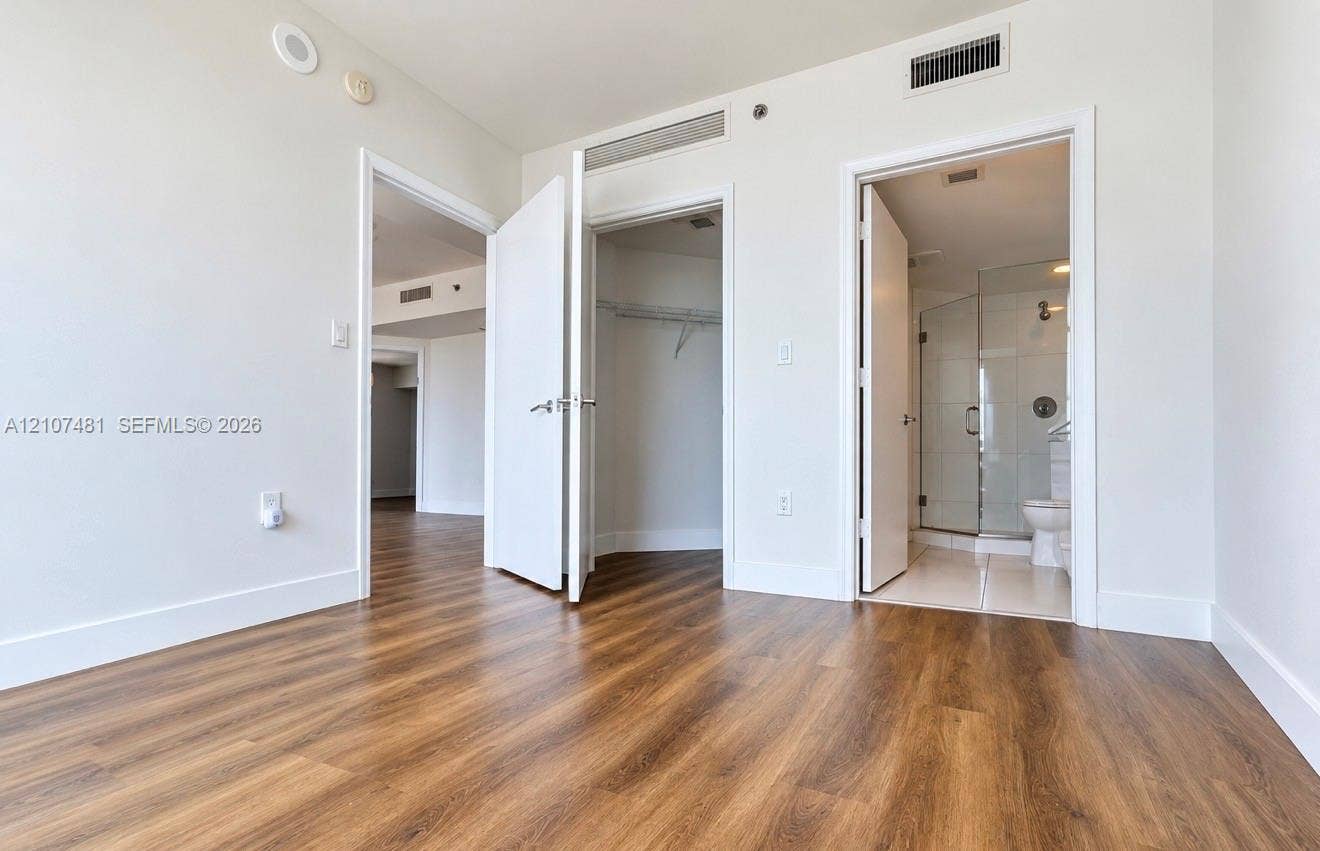 55 SE 6th Street, #2802, Miami, FL 33131 Wood-finish flooring, interior doors with lever-style hardware, reach-in closet, and an en suite bathroom featuring a glass-enclosed shower