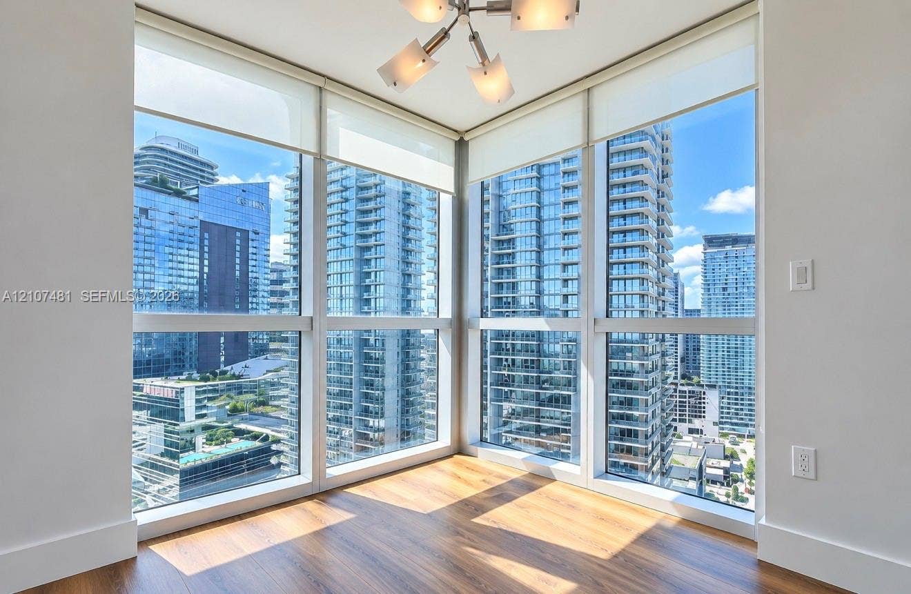 55 SE 6th Street, #2802, Miami, FL 33131 Floor-to-ceiling corner windows, wood-finish flooring, and a modern multi-arm light fixture