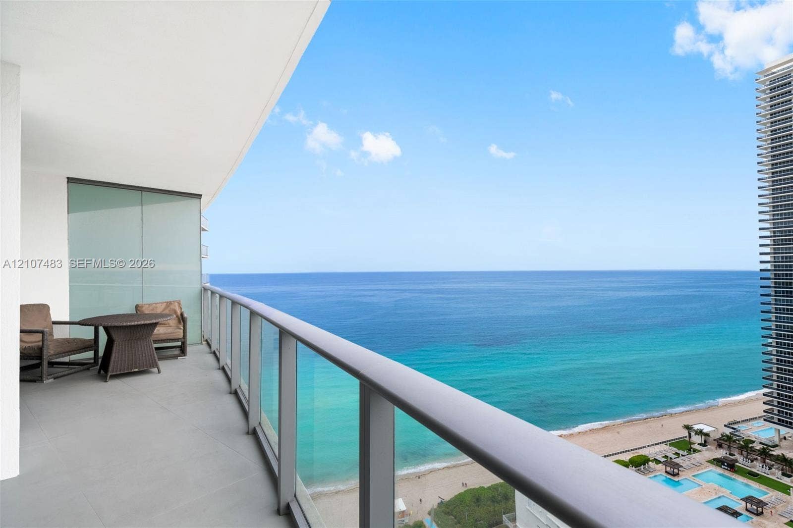 4111 S Ocean Drive, #2407, Hollywood, FL 33019 Private balcony featuring neutral-toned tile flooring, minimalist metal railings, and clear glass panels