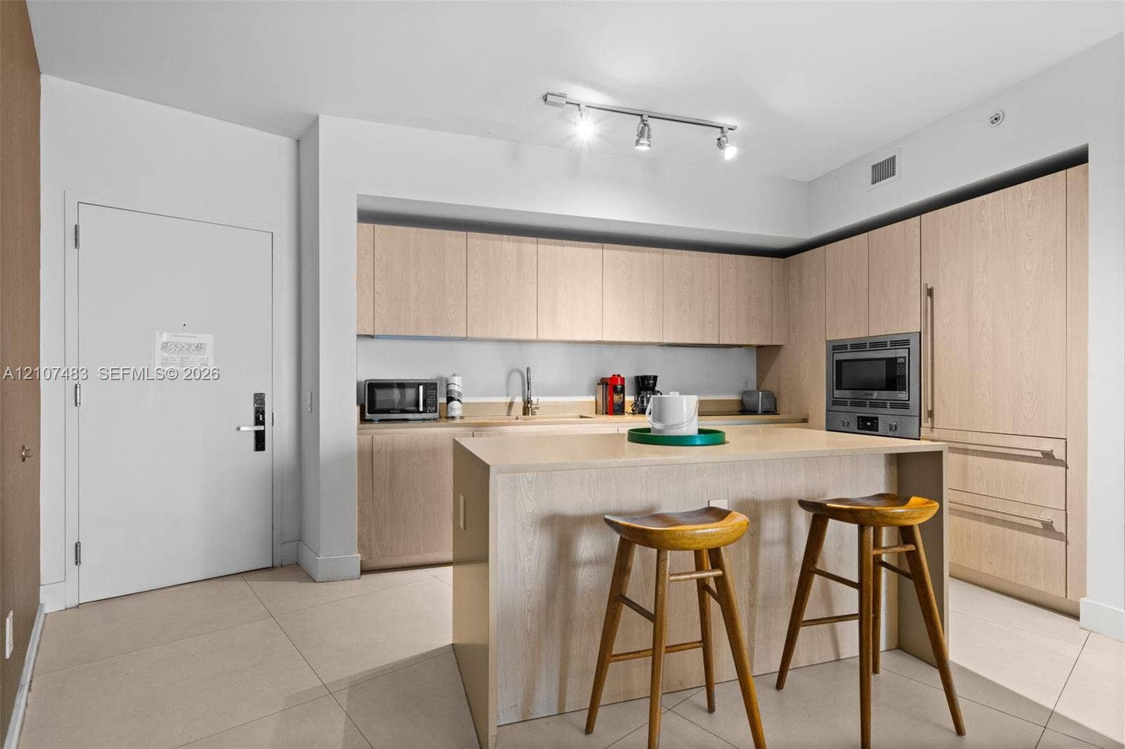 4111 S Ocean Drive, #2407, Hollywood, FL 33019 Kitchen featuring light-toned cabinetry, a built-in oven, large-format tile flooring, a center island with counter seating, and track lighting