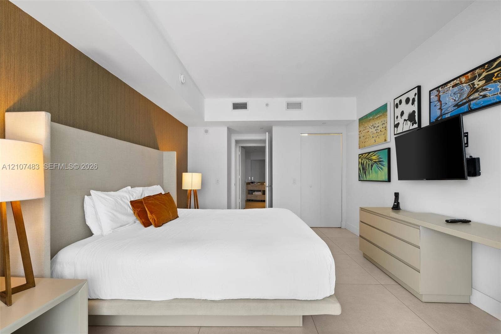 4111 S Ocean Drive, #2407, Hollywood, FL 33019 Spacious room featuring a floor-to-ceiling accent wall, tile flooring, built-in cabinetry with an integrated desk surface, and neutral wall tones