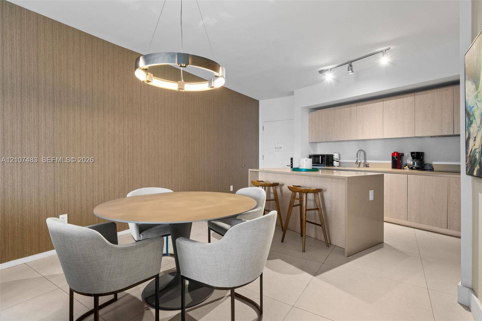 4111 S Ocean Drive, #2407, Hollywood, FL 33019 Kitchen featuring light-toned wood cabinetry, stone-surface island, tile flooring, modern circular statement pendant light, and track lighting