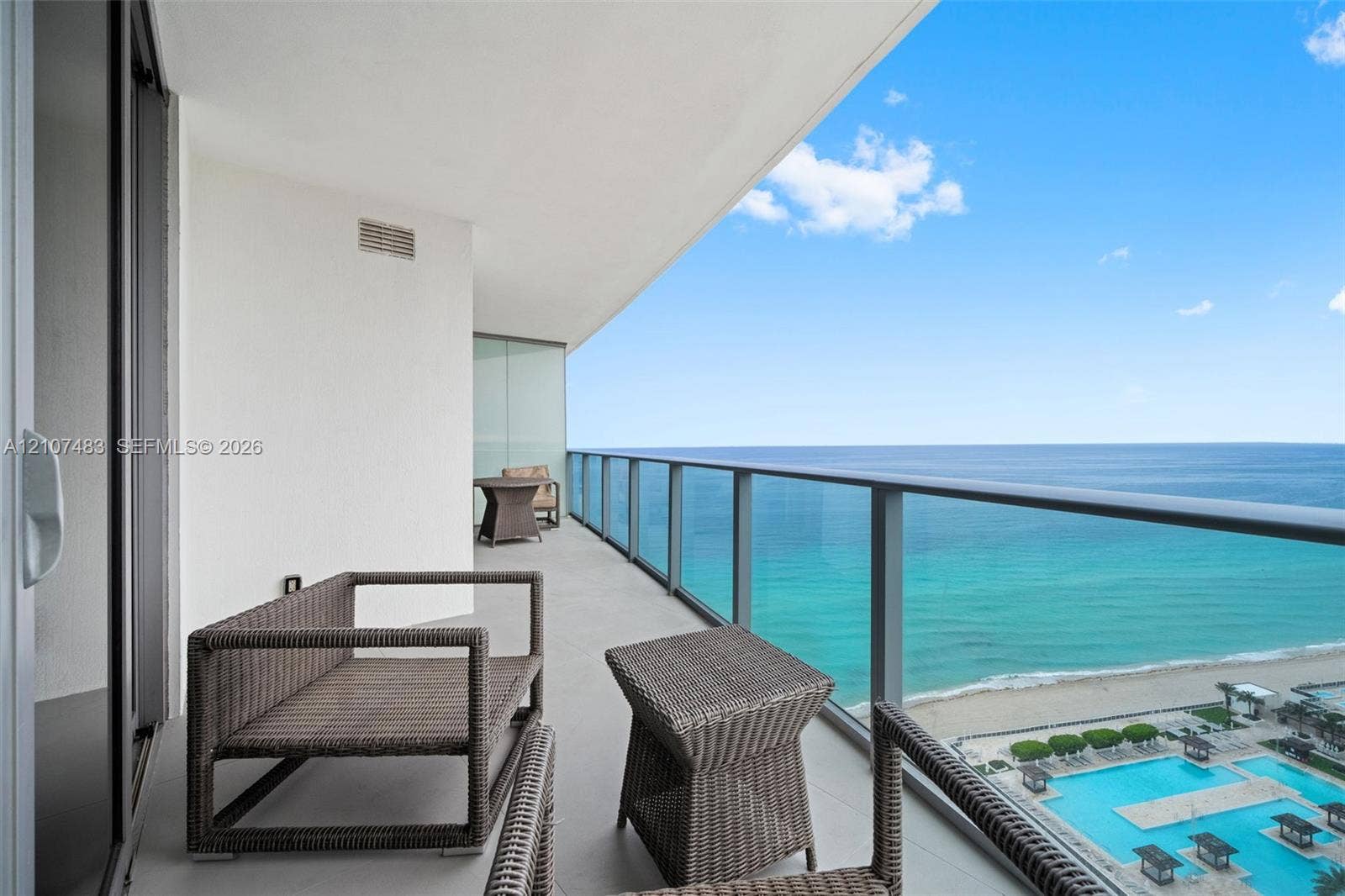 4111 S Ocean Drive, #2407, Hollywood, FL 33019 Covered balcony featuring a sleek glass-panel railing, neutral tiled flooring, and expansive ocean and coastal scenery
