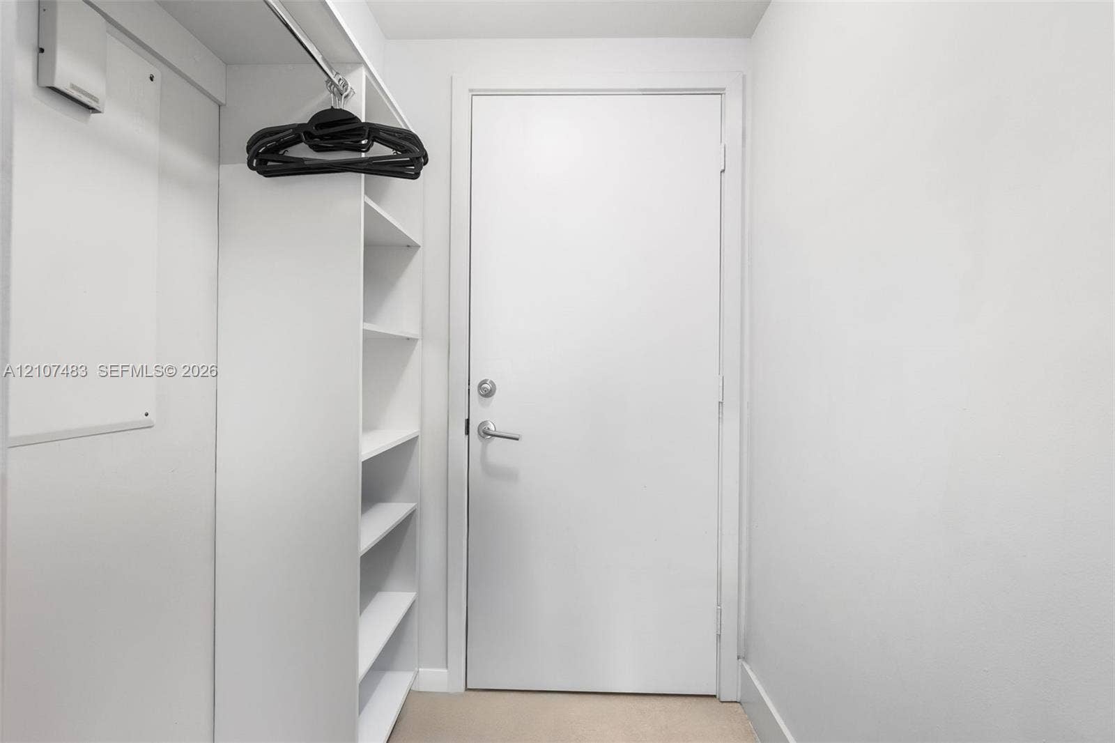 4111 S Ocean Drive, #2407, Hollywood, FL 33019 Storage area featuring built-in white shelving, a metal garment rod, and a solid-core interior door with satin-finish hardware