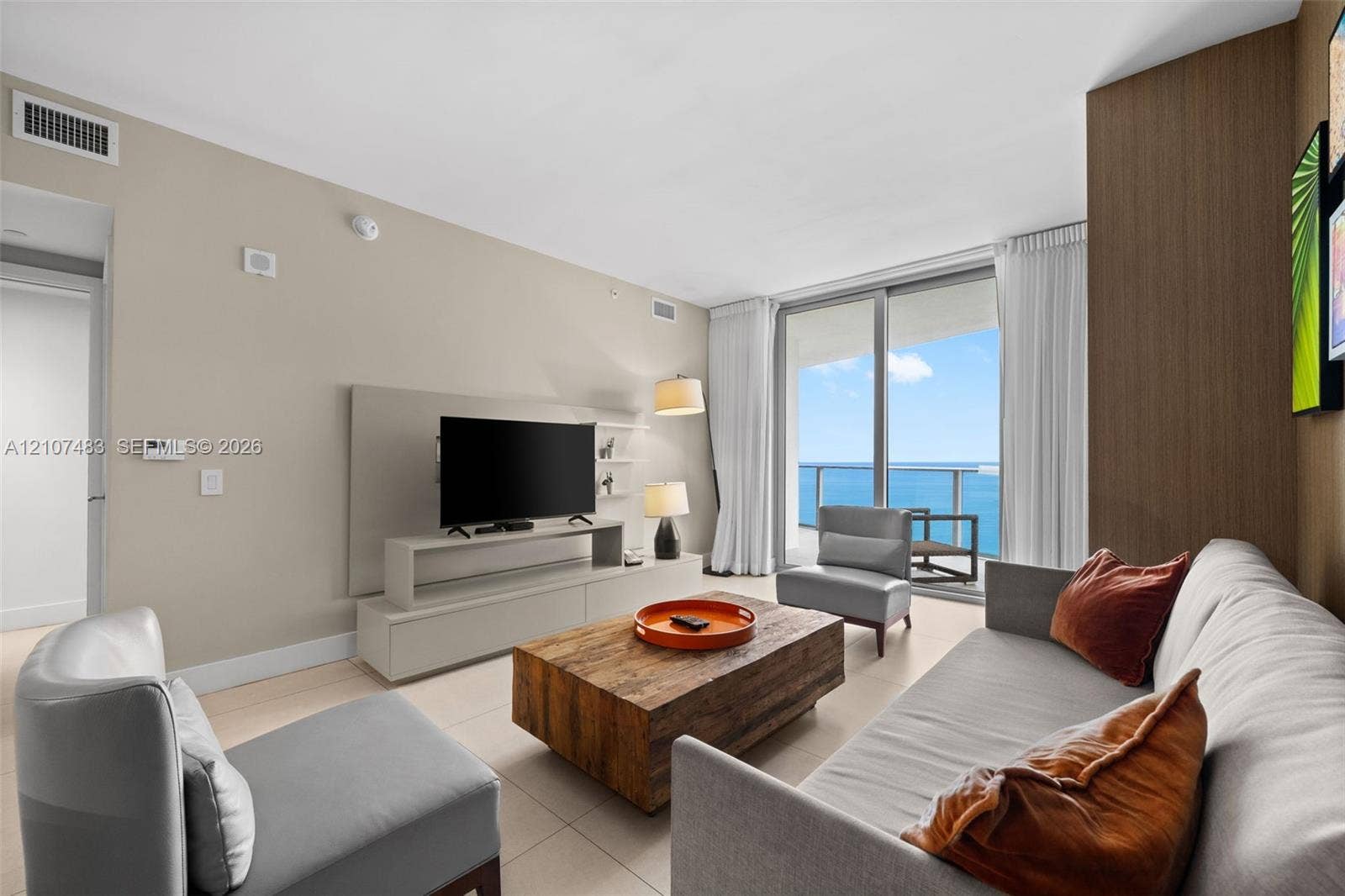 4111 S Ocean Drive, #2407, Hollywood, FL 33019 Living area featuring floor-to-ceiling glass sliding doors, ocean backdrop, built-in wall cabinetry, and large-format tile flooring
