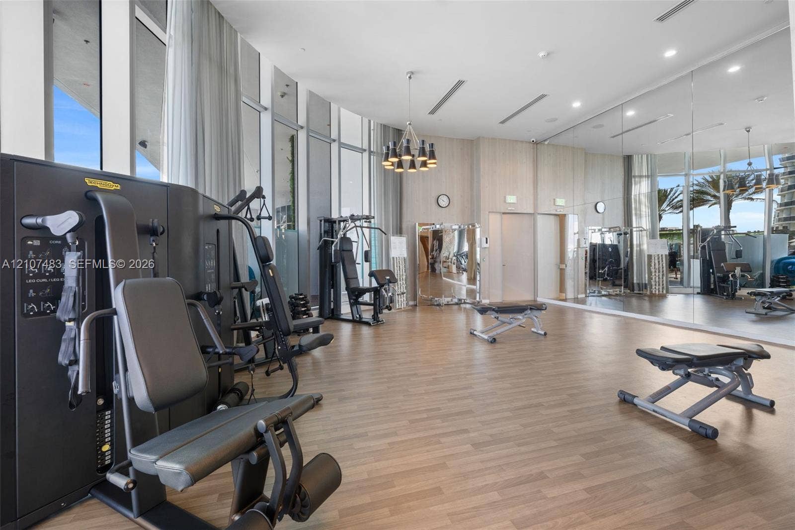 4111 S Ocean Drive, #2407, Hollywood, FL 33019 Fitness center featuring floor-to-ceiling windows, wood-finish flooring, mirrored wall panels, and a multi-light chandelier