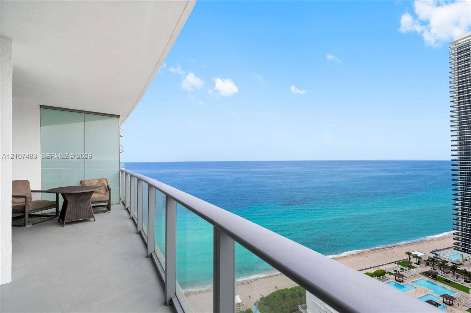 4111 S Ocean Drive, #2407, Hollywood, FL 33019 Covered balcony featuring concrete flooring, a glass-panel railing, and an expansive horizon of the ocean