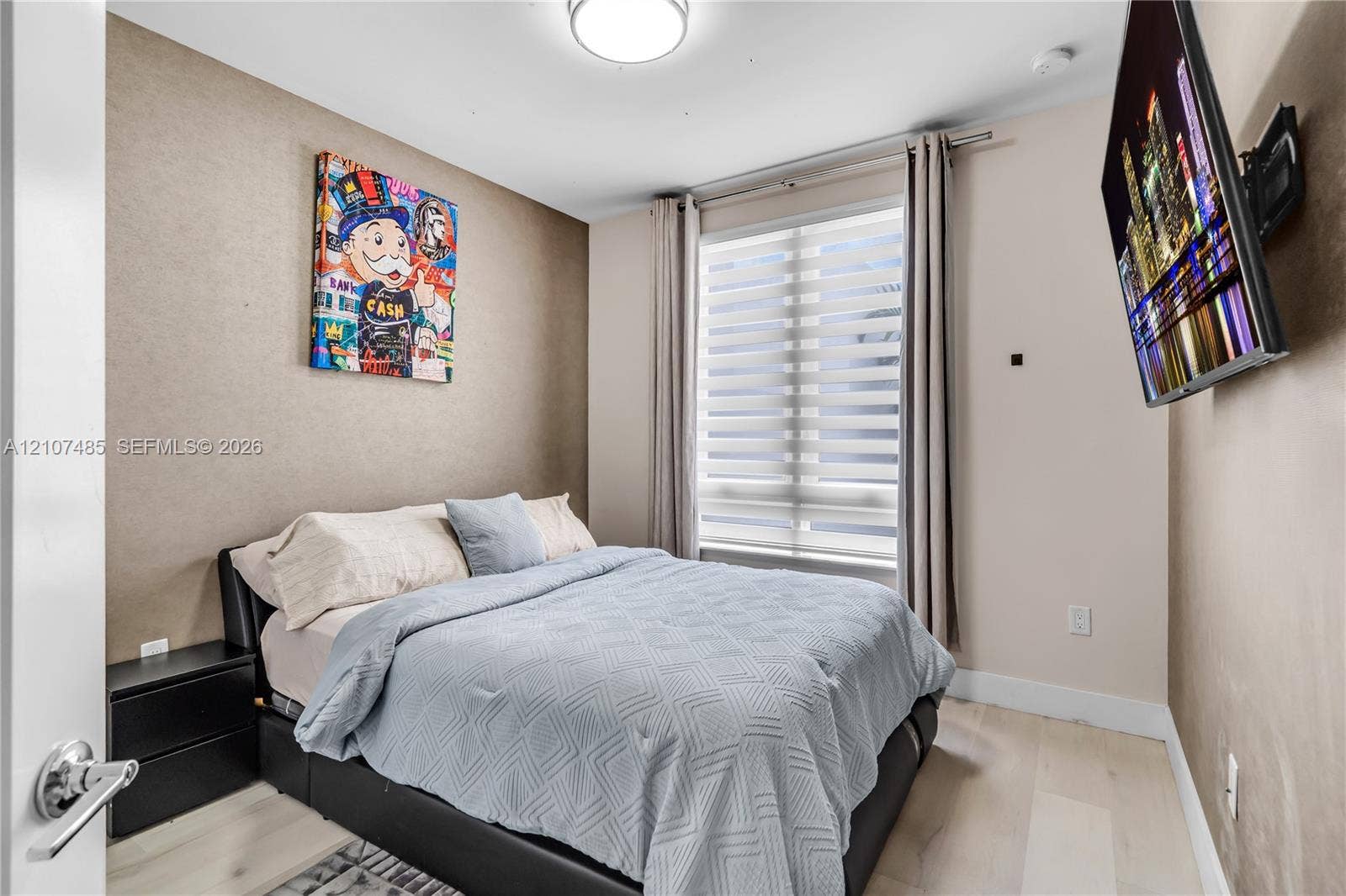 10545 NW 63rd Terrace, Doral, FL 33178 Neutral-toned wall finish, wood-finish flooring, and large window featuring dual-layered adjustable blinds, illuminated by a flush-mount overhead light fixture