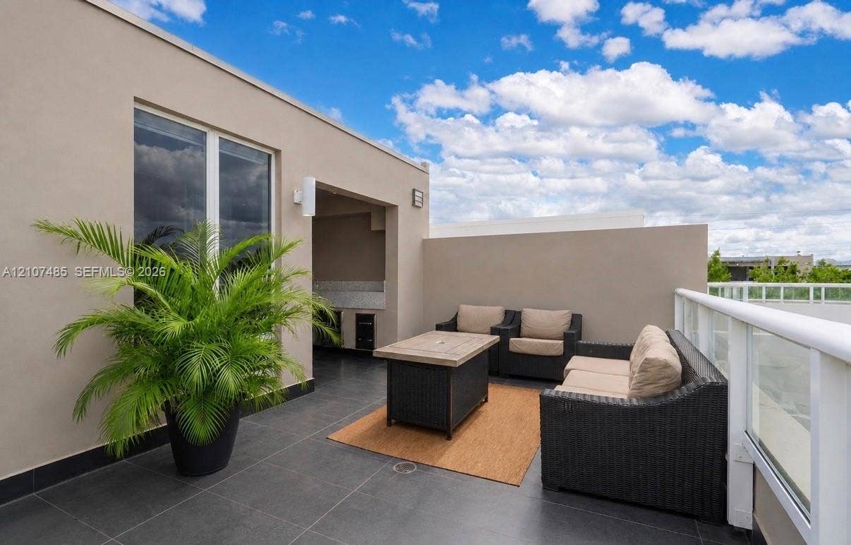 10545 NW 63rd Terrace, Doral, FL 33178 Rooftop terrace featuring charcoal tile flooring, integrated outdoor kitchen cabinetry with stone countertops, and a white glass-panel railing