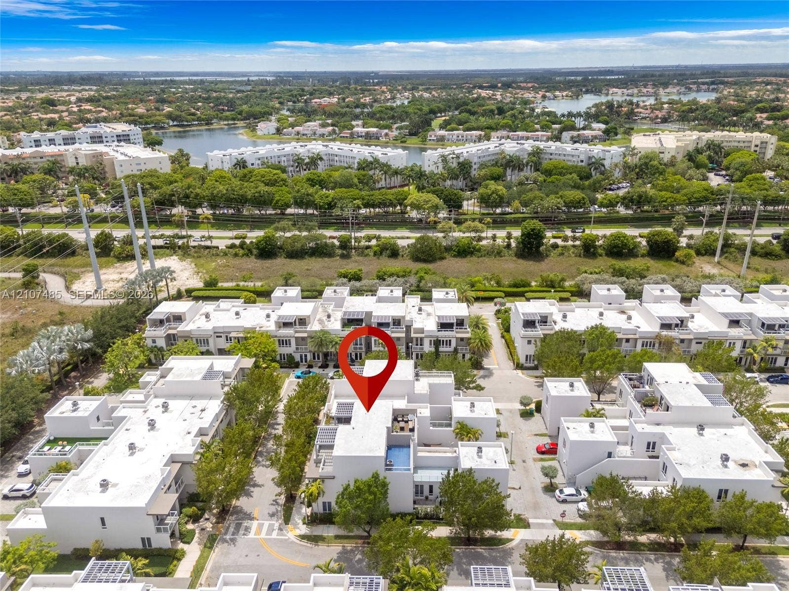 10545 NW 63rd Terrace, Doral, FL 33178 Aerial perspective of a multi-level residential property featuring a rooftop terrace, private pool, modern exterior architecture, and mature landscaping