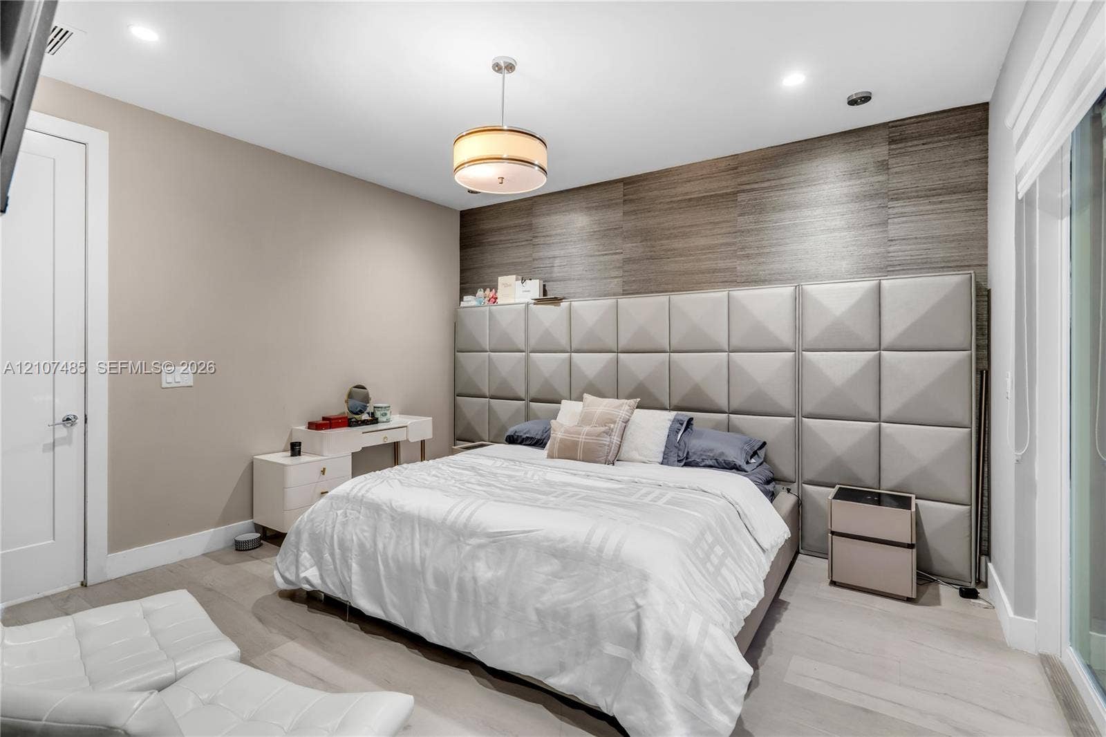 10545 NW 63rd Terrace, Doral, FL 33178 Custom wall-mounted upholstered grid headboard, horizontal wood-texture wall paneling, drum pendant light fixture, recessed ceiling lighting, and wood-finish flooring
