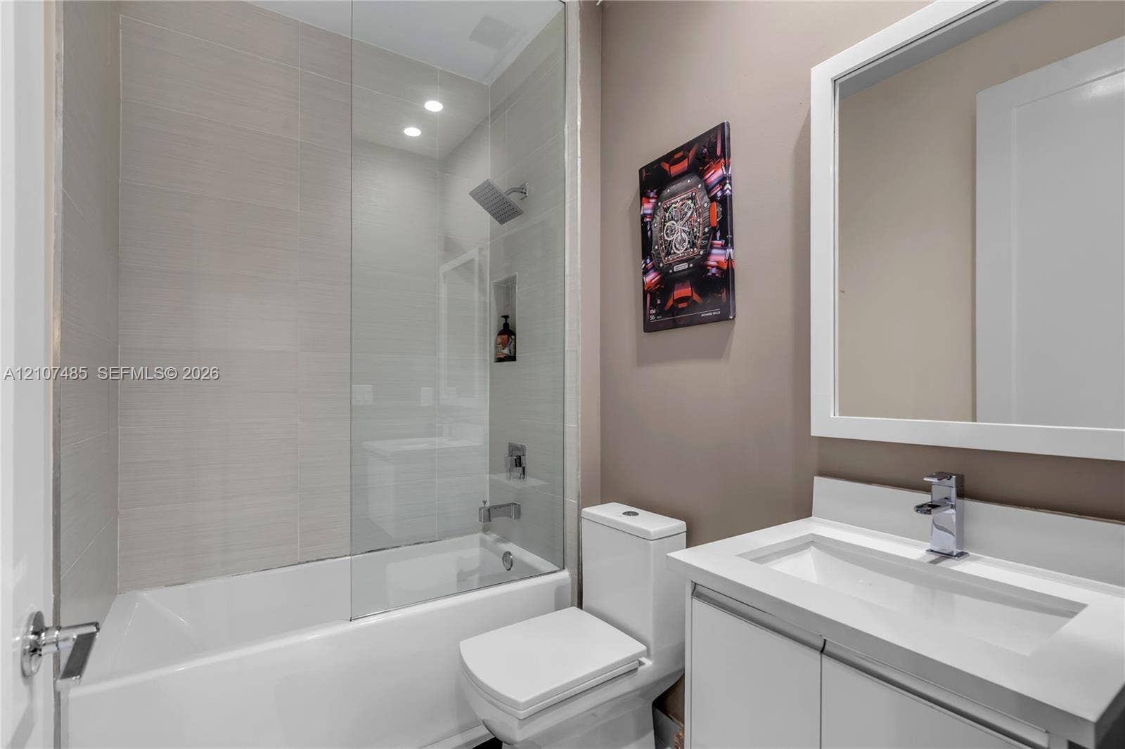 10545 NW 63rd Terrace, Doral, FL 33178 Bathroom featuring a white vanity with a rectangular sink, framed wall mirror, glass shower partition, tile-surround tub, and rainfall showerhead