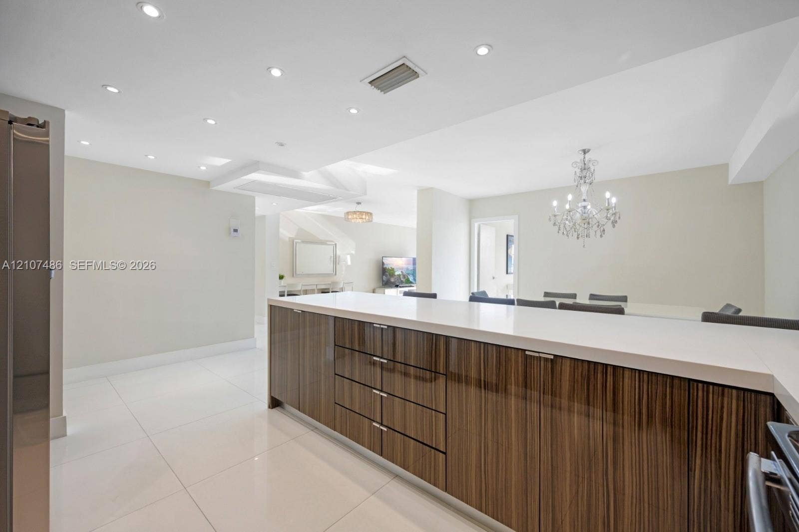 19370 Collins Avenue, #916, Sunny Isles Beach, Sunny Isles Beach, FL 33160 Kitchen island featuring high-gloss wood-grain cabinetry, quartz countertops, large-format tile flooring, recessed ceiling lighting, and a tiered crystal chandelier