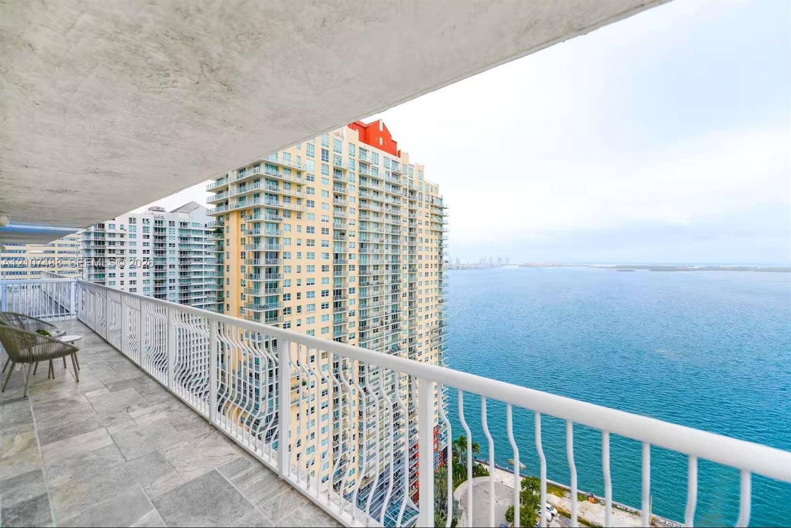Covered balcony featuring stone-tile flooring and a white metal railing