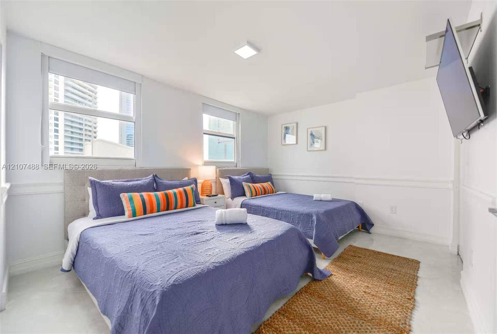 Neutral-toned room featuring high-gloss flooring, horizontal chair rail molding, dual large-format windows, and square LED ceiling lighting