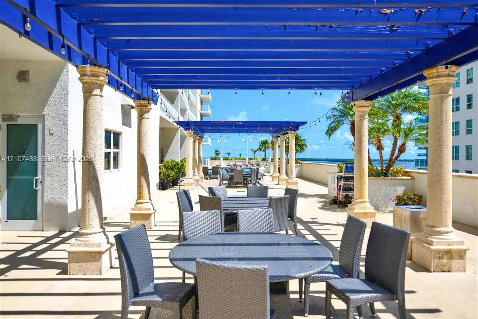 Outdoor terrace featuring a pergola with stone-finish columns, concrete flooring, and string lighting