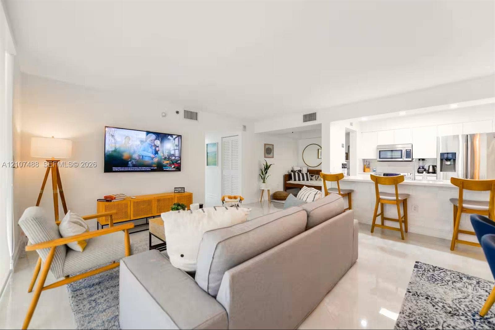 Open-concept living space featuring high-gloss tile flooring, recessed lighting, white cabinetry, and a breakfast bar