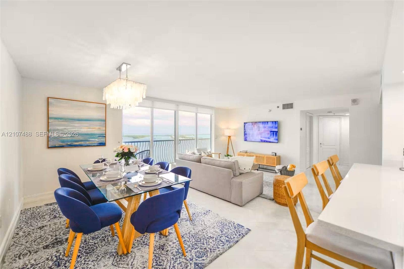 Open-concept interior featuring large-format tile flooring, floor-to-ceiling glass sliding doors, built-in recessed lighting, and a crystal-style chandelier