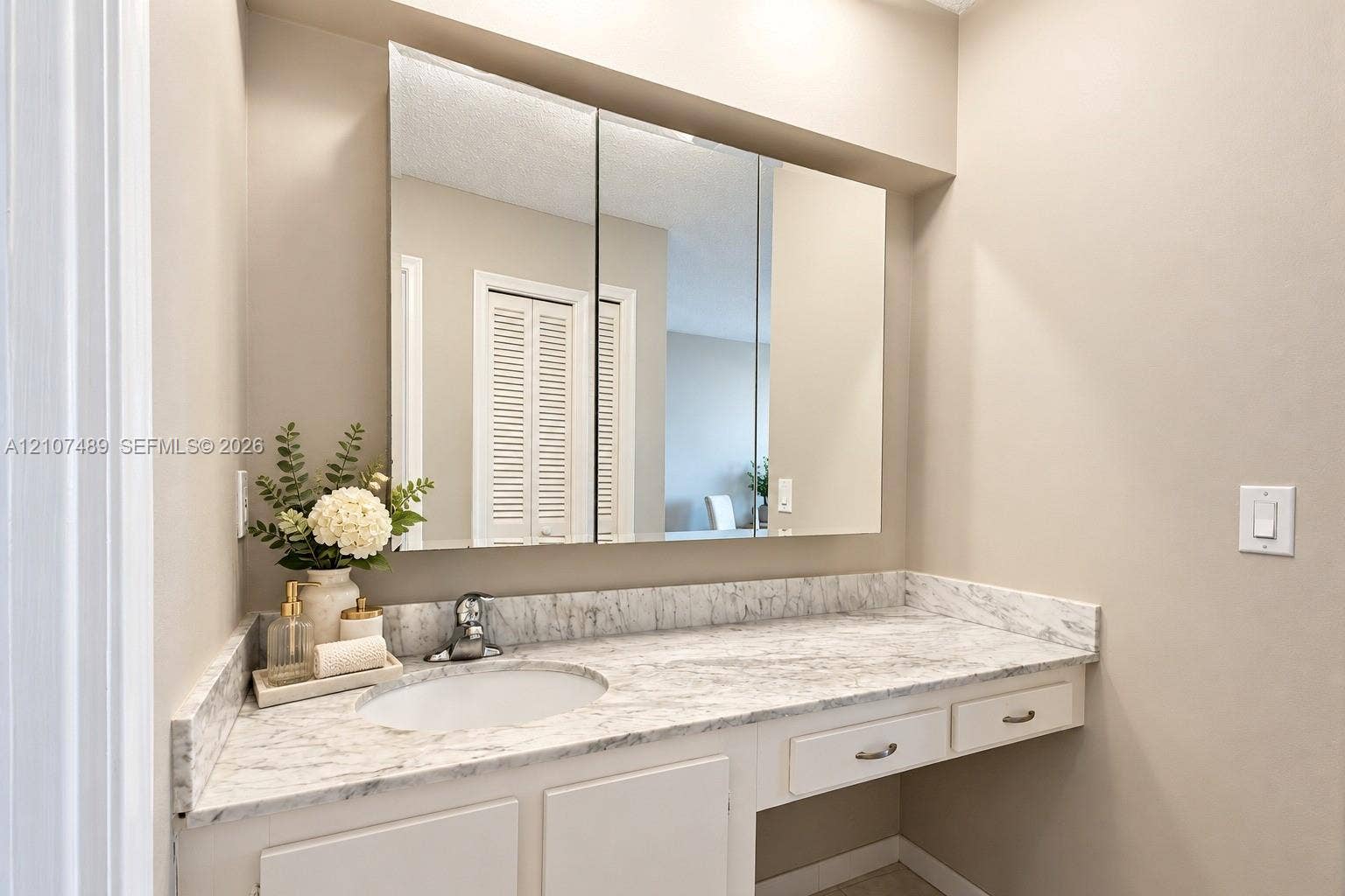 2000 S Ocean Boulevard, #9N, Lauderdale-By-The-Sea, Lauderdale By The Sea, FL 33062 Vanity featuring a stone-patterned countertop, integrated basin with a chrome faucet, tri-fold mirrored medicine cabinet, and built-in drawers