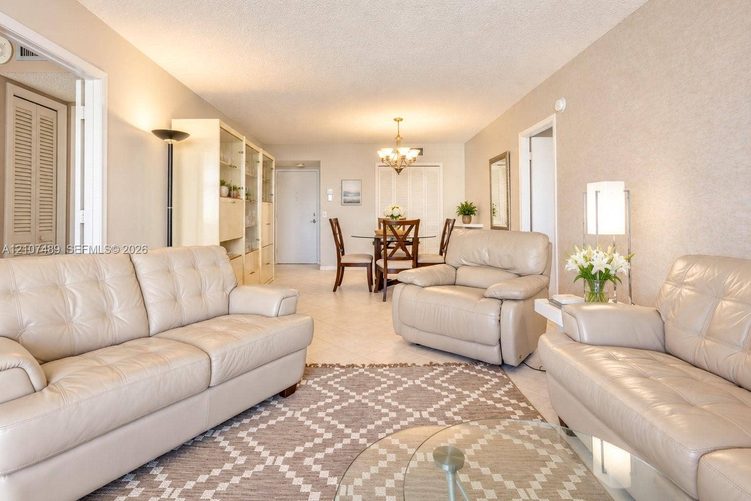 2000 S Ocean Boulevard, #9N, Lauderdale-By-The-Sea, Lauderdale By The Sea, FL 33062 Neutral-toned interior space featuring light-colored tile flooring, built-in shelving, textured wall surfaces, and a multi-arm chandelier