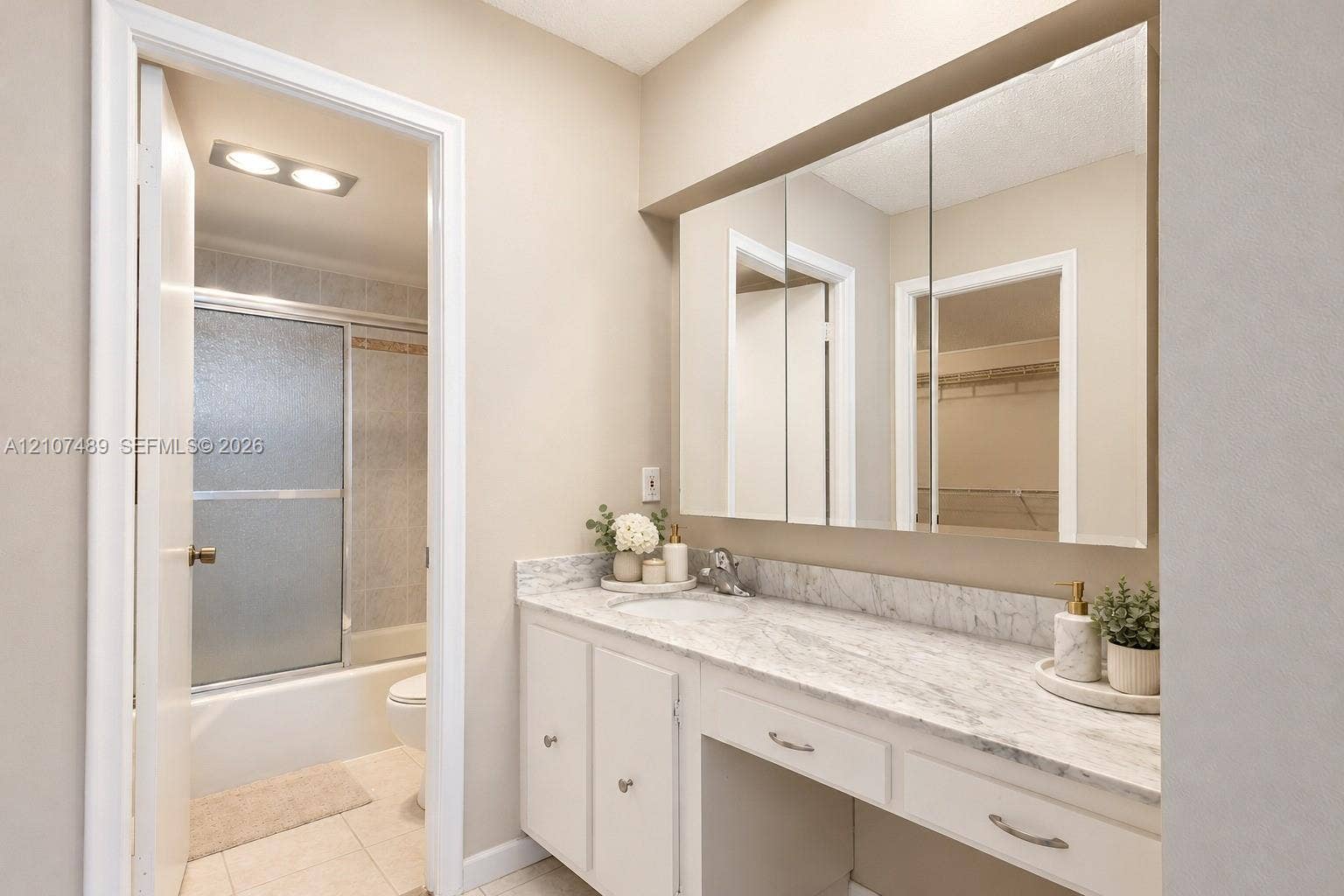 2000 S Ocean Boulevard, #9N, Lauderdale-By-The-Sea, Lauderdale By The Sea, FL 33062 Vanity featuring a stone-look countertop, integrated sink, built-in medicine cabinet, and a dedicated seated vanity space, complete with a separate area containing a tub-shower combination with sliding glass doors