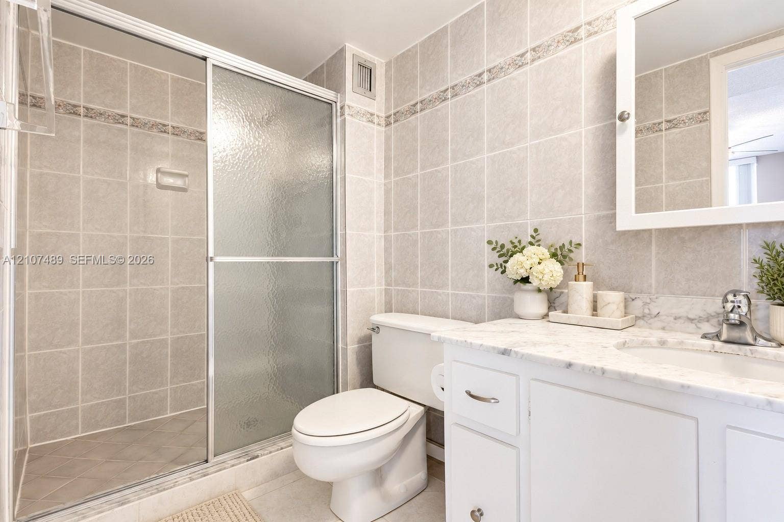 2000 S Ocean Boulevard, #9N, Lauderdale-By-The-Sea, Lauderdale By The Sea, FL 33062 Bathroom featuring a shower with a sliding glass door, white vanity with stone-finish countertop, undermount sink, and tiled wall surround