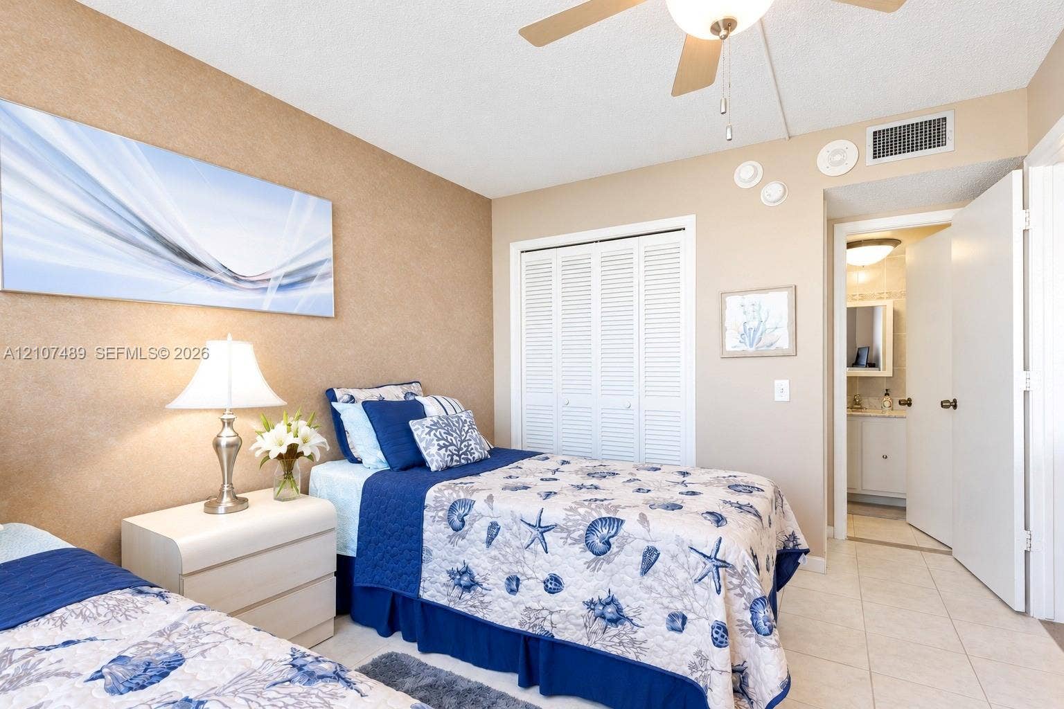 2000 S Ocean Boulevard, #9N, Lauderdale-By-The-Sea, Lauderdale By The Sea, FL 33062 Bedroom featuring textured accent wall, louvered-door closet, ceiling fan with integrated lighting, and tile flooring