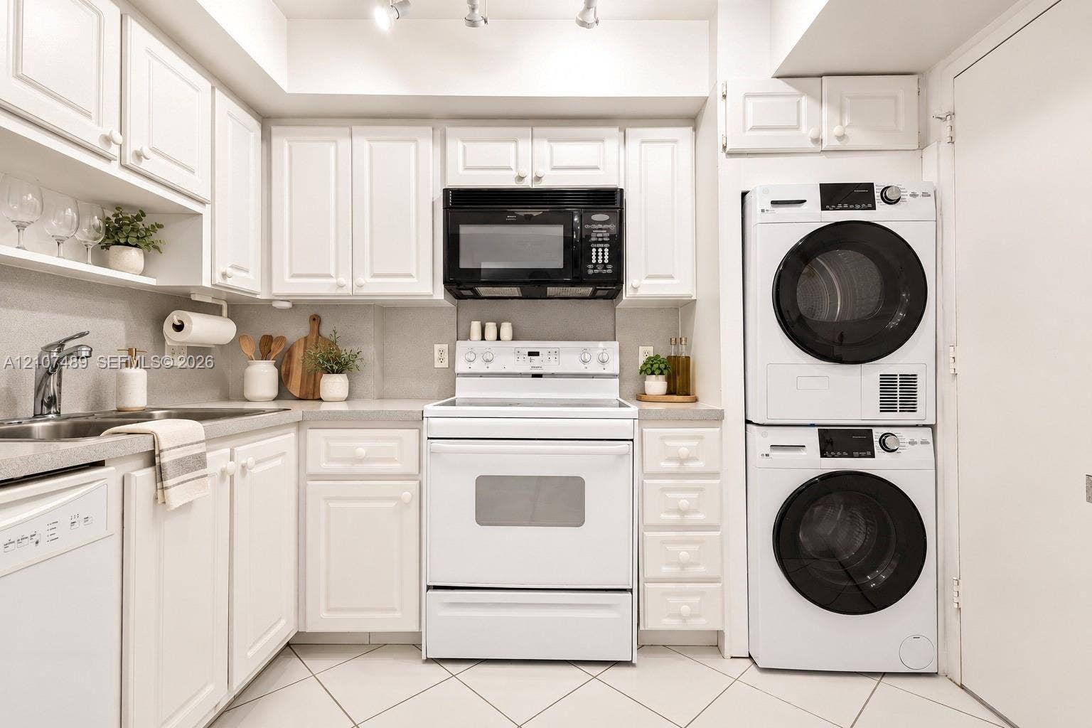 2000 S Ocean Boulevard, #9N, Lauderdale-By-The-Sea, Lauderdale By The Sea, FL 33062 Kitchen featuring shaker-style cabinetry, solid-surface countertops, stainless steel sink with high-arc faucet, integrated laundry center, and tile flooring