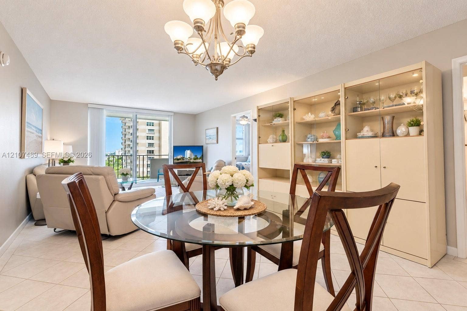 2000 S Ocean Boulevard, #9N, Lauderdale-By-The-Sea, Lauderdale By The Sea, FL 33062 Living area featuring light-toned tile flooring, a multi-bulb chandelier, built-in floor-to-ceiling cabinetry with glass shelving, and sliding glass doors providing outdoor access