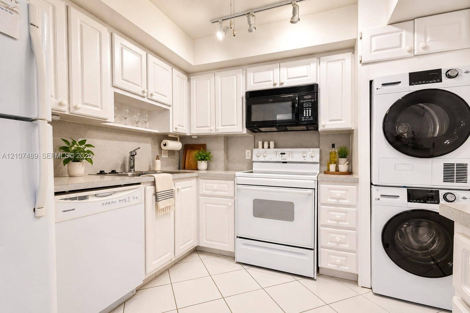 2000 S Ocean Boulevard, #9N, Lauderdale-By-The-Sea, Lauderdale By The Sea, FL 33062 Kitchen featuring white cabinetry, solid-surface countertops, tile flooring, track lighting, and a built-in laundry unit