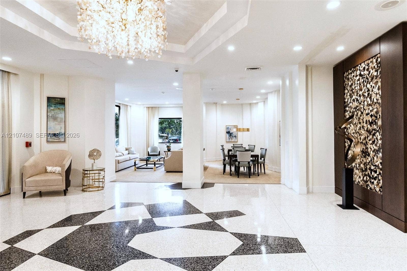 2000 S Ocean Boulevard, #9N, Lauderdale-By-The-Sea, Lauderdale By The Sea, FL 33062 Polished stone flooring featuring a geometric inlay, recessed tray ceiling with a crystal chandelier, and a floor-to-ceiling decorative accent wall with textured paneling