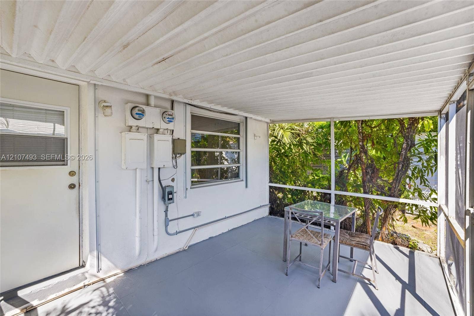 2645 NE 32nd Street, Fort Lauderdale, FL 33306 Screened-in porch featuring a corrugated metal ceiling, painted concrete flooring, and horizontal sliding windows