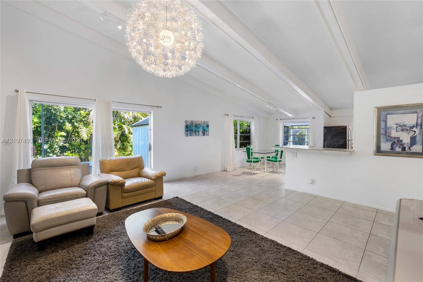 2645 NE 32nd Street, Fort Lauderdale, FL 33306 Vaulted ceilings with exposed beams, large-format tile flooring, oversized spherical pendant lighting, track lighting, and a breakfast bar counter