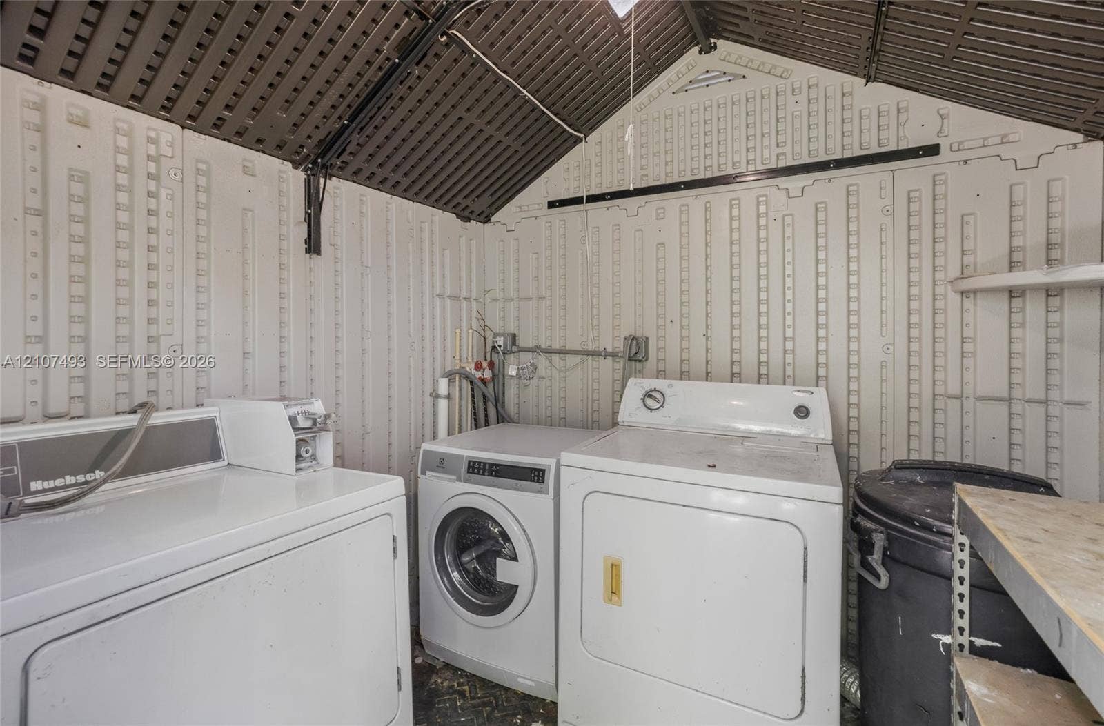 2645 NE 32nd Street, Fort Lauderdale, FL 33306 Utility structure featuring high-vaulted corrugated paneling, integrated wall-mounted shelving, and exposed electrical conduits