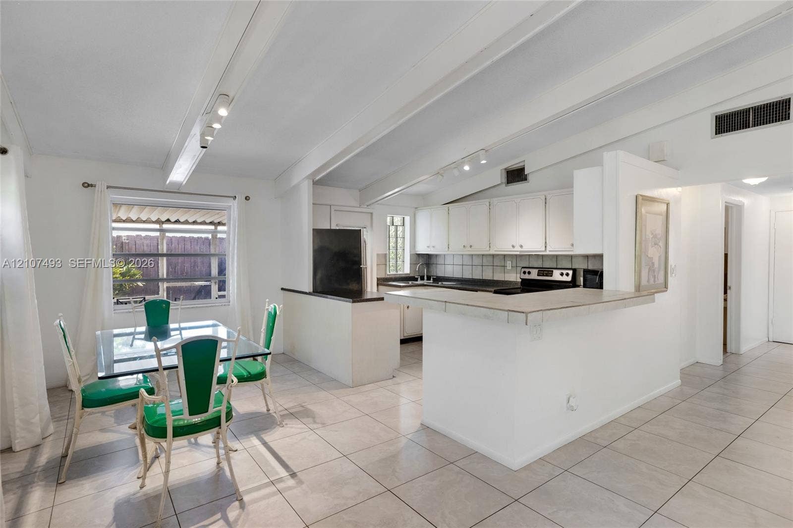 2645 NE 32nd Street, Fort Lauderdale, FL 33306 Vaulted ceilings with exposed beams, tile flooring, breakfast bar, and track lighting